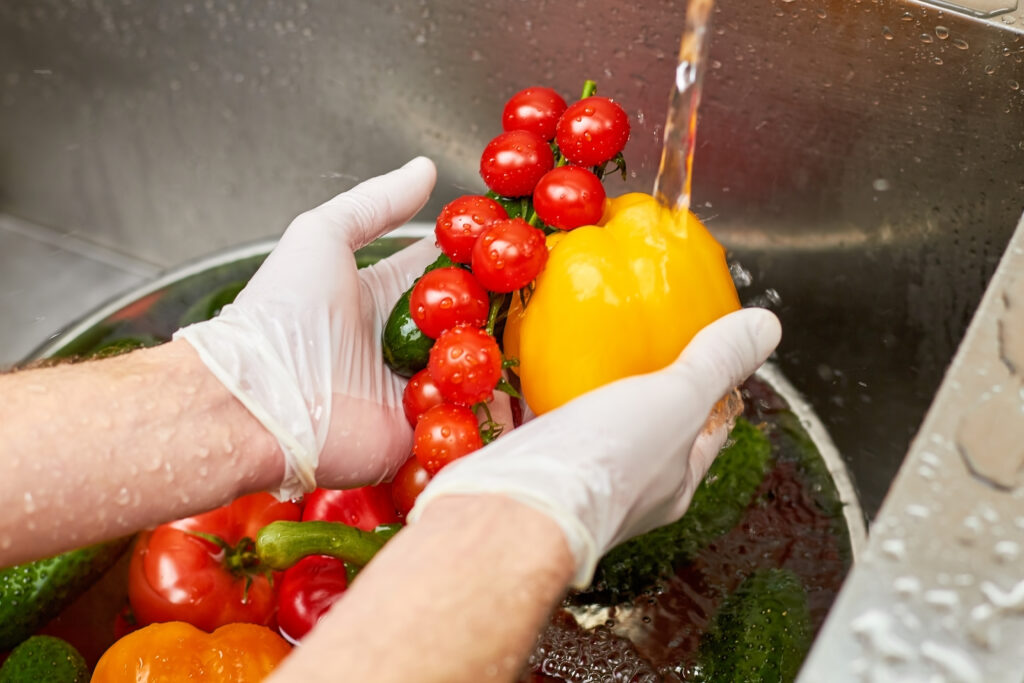 Chef hands holding bell pepper, stem of cherry tomatoes and cucumber.